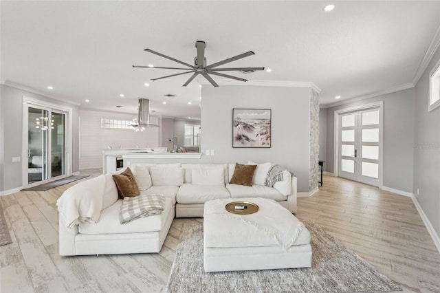 living room featuring ceiling fan with notable chandelier, light hardwood / wood-style floors, and ornamental molding