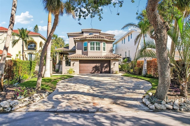 mediterranean / spanish-style house featuring a garage, decorative driveway, a tile roof, and stucco siding