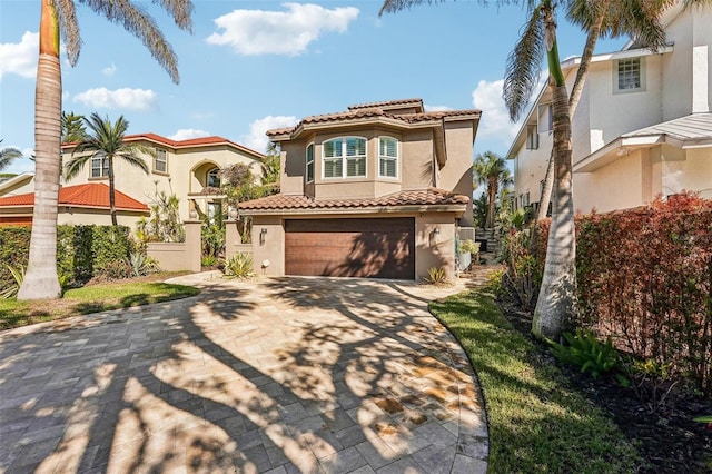 mediterranean / spanish-style house with driveway, an attached garage, a tiled roof, and stucco siding