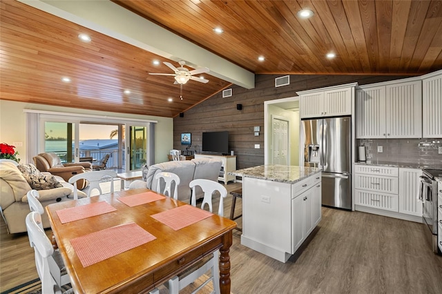 dining room with ceiling fan, dark wood-type flooring, lofted ceiling with beams, wooden ceiling, and wood walls