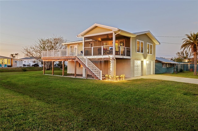 back house at dusk featuring a yard, a garage, and a wooden deck