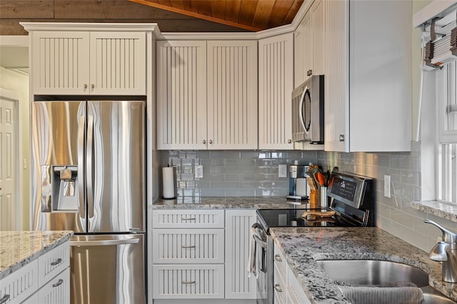 kitchen featuring appliances with stainless steel finishes, tasteful backsplash, vaulted ceiling, and sink