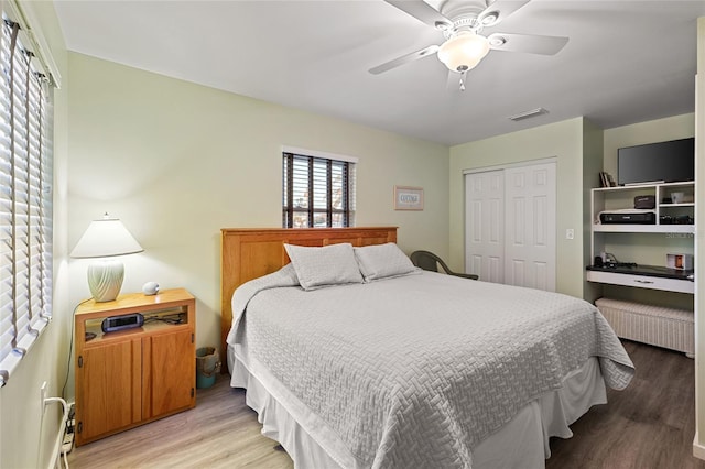 bedroom featuring ceiling fan, radiator heating unit, light hardwood / wood-style flooring, and a closet