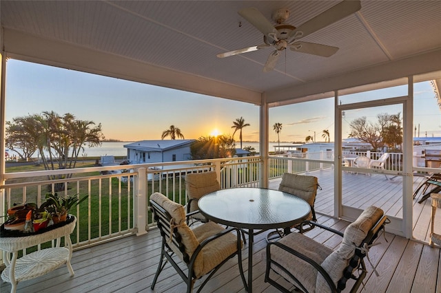 deck at dusk featuring ceiling fan and a water view