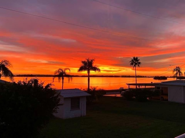 yard at dusk with a water view and a storage shed