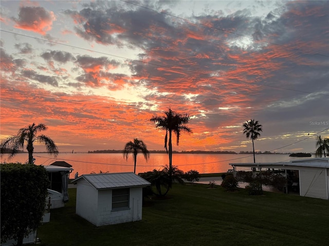 yard at dusk with a water view and a shed