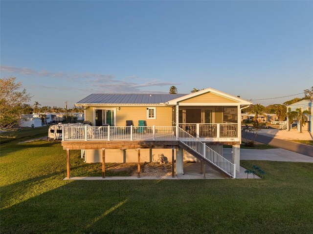 back of house featuring a sunroom and a lawn