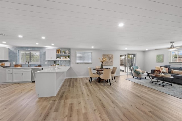 kitchen with white cabinetry, dishwasher, tasteful backsplash, kitchen peninsula, and light hardwood / wood-style floors