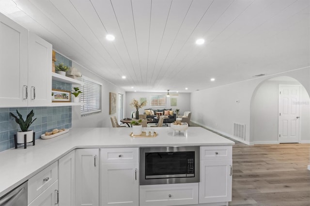 kitchen featuring kitchen peninsula, built in microwave, and white cabinets