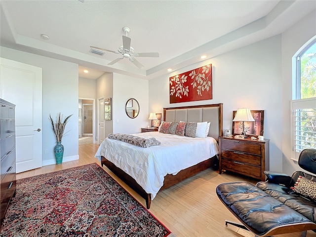 bedroom featuring a raised ceiling, ceiling fan, and light hardwood / wood-style floors