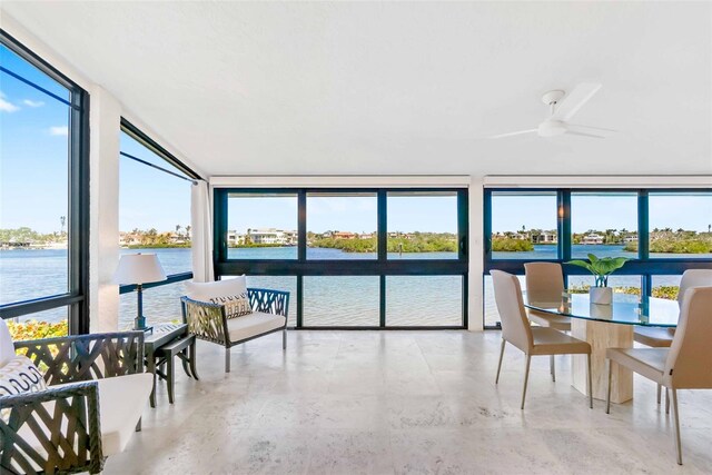 sunroom featuring a water view and a ceiling fan