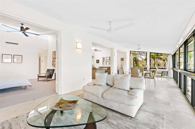 living room featuring expansive windows, visible vents, and a ceiling fan