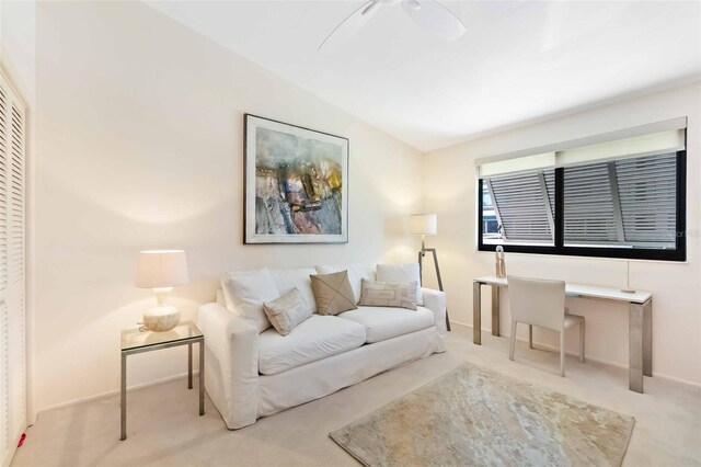 living area featuring lofted ceiling, carpet, baseboards, and a ceiling fan