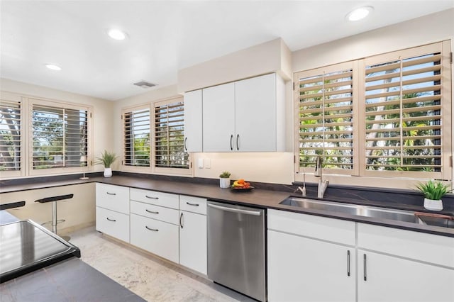 kitchen featuring visible vents, white cabinets, dishwasher, dark countertops, and a sink