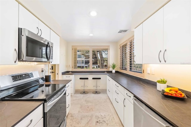 kitchen with visible vents, dark countertops, stainless steel appliances, white cabinetry, and recessed lighting