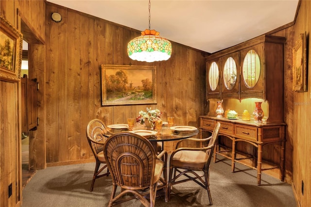 carpeted dining room featuring wooden walls