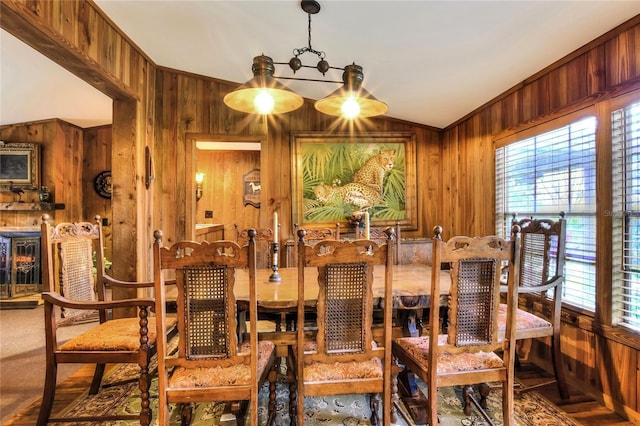 dining space featuring vaulted ceiling, wooden walls, and crown molding