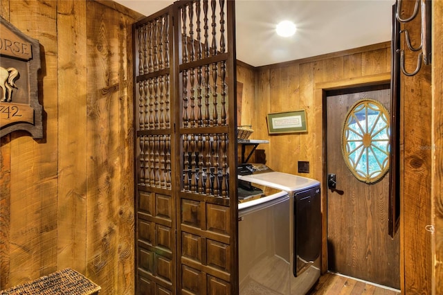 laundry area featuring wood walls, washing machine and dryer, and wood-type flooring