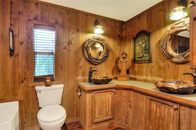 bathroom with vanity, toilet, and wood walls