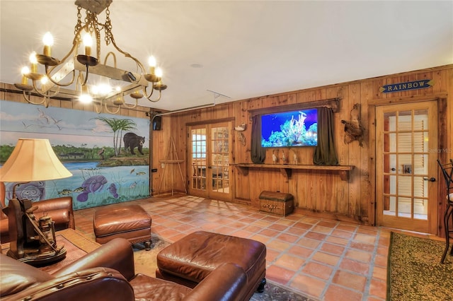 living room featuring a notable chandelier, wood walls, light tile patterned floors, and french doors