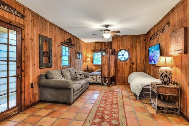 interior space with ceiling fan, ornamental molding, and wooden walls