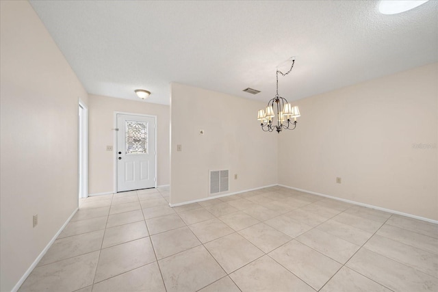 interior space featuring light tile patterned floors, a textured ceiling, and a chandelier