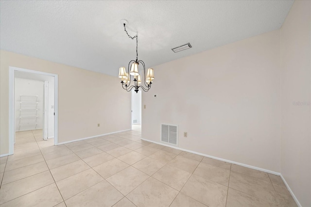 unfurnished room featuring a textured ceiling, a notable chandelier, and light tile patterned flooring