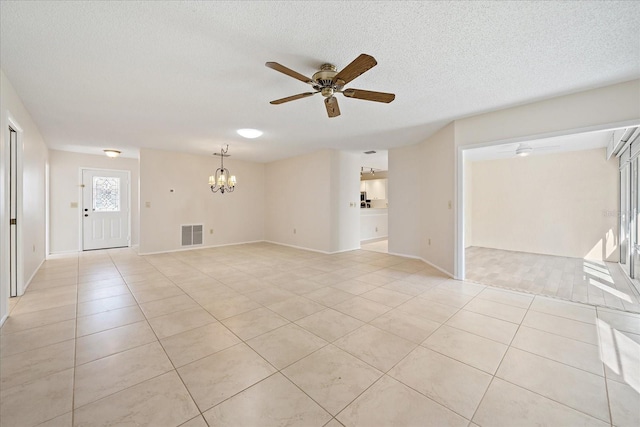 spare room featuring ceiling fan with notable chandelier, light tile patterned floors, and a textured ceiling