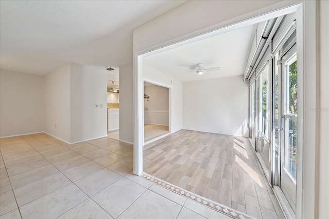 unfurnished room featuring a textured ceiling, light wood-type flooring, and ceiling fan