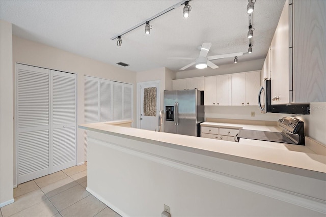 kitchen featuring ceiling fan, a textured ceiling, appliances with stainless steel finishes, light tile patterned flooring, and white cabinetry