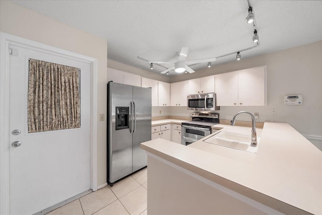 kitchen with ceiling fan, sink, stainless steel appliances, kitchen peninsula, and a textured ceiling