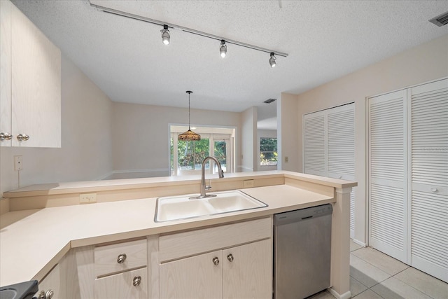 kitchen with dishwasher, sink, hanging light fixtures, a textured ceiling, and light tile patterned floors