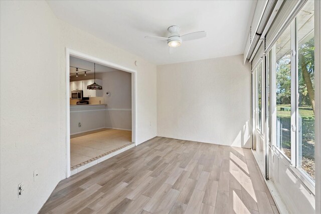 spare room featuring plenty of natural light, ceiling fan, and light hardwood / wood-style flooring