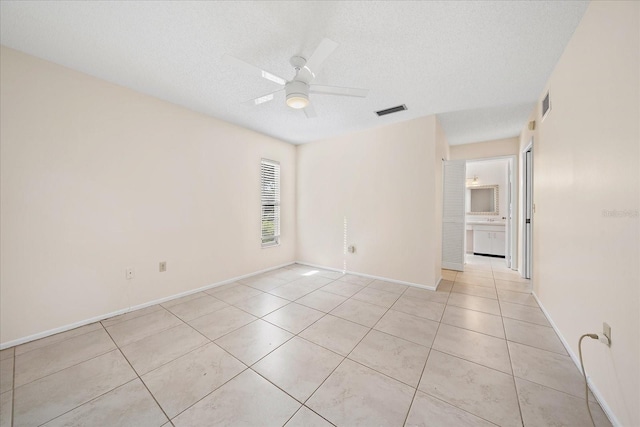 tiled empty room with ceiling fan and a textured ceiling