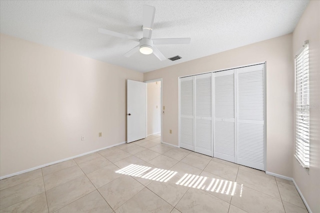 unfurnished bedroom with multiple windows, light tile patterned floors, a closet, and ceiling fan