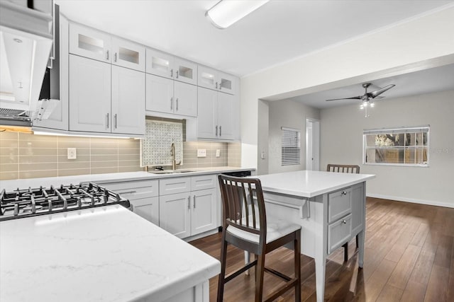 kitchen with white cabinets, decorative backsplash, dark hardwood / wood-style floors, ceiling fan, and light stone countertops