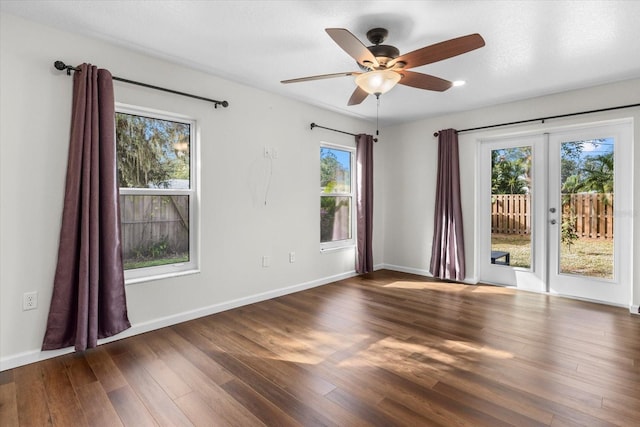 empty room featuring plenty of natural light, ceiling fan, and dark hardwood / wood-style flooring