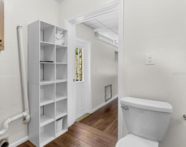 bathroom with wood-type flooring, toilet, and a drop ceiling