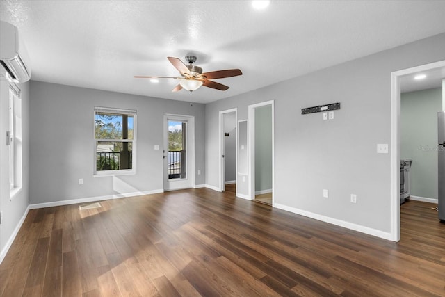 spare room with a wall unit AC, ceiling fan, dark hardwood / wood-style flooring, and a textured ceiling