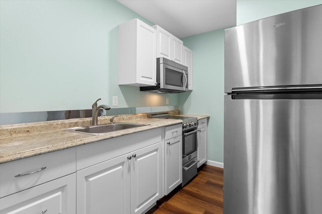 kitchen featuring dark wood-type flooring, sink, light stone counters, white cabinetry, and stainless steel appliances