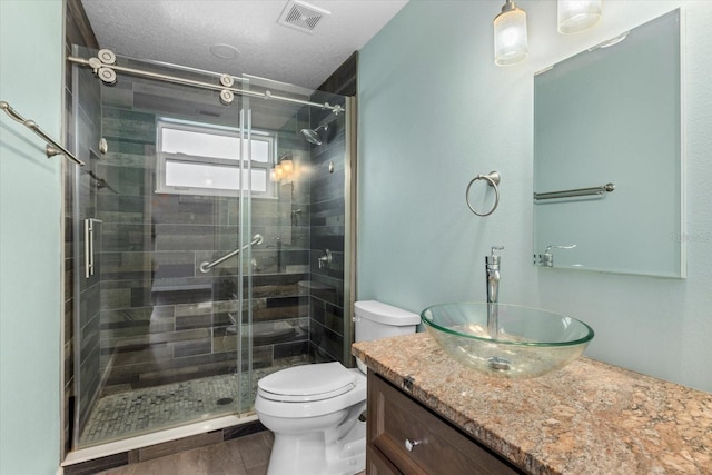 bathroom with vanity, a textured ceiling, hardwood / wood-style flooring, toilet, and a shower with shower door