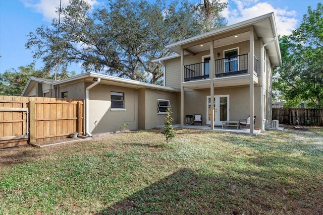 back of property featuring a balcony, a yard, a patio, and french doors