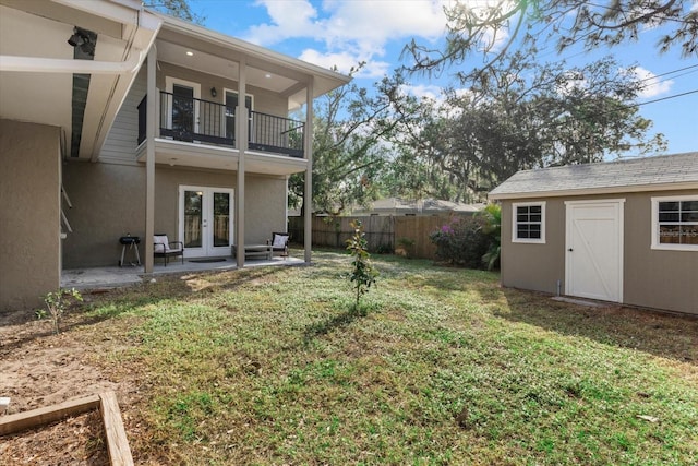 view of yard with a balcony, a patio, french doors, and a storage shed