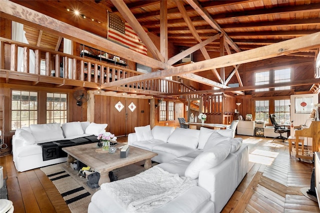 living room with wood ceiling, wooden walls, high vaulted ceiling, beamed ceiling, and hardwood / wood-style floors