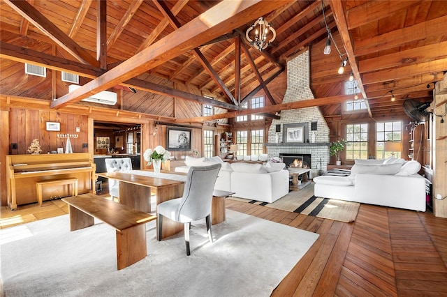 dining area featuring beam ceiling, light wood-type flooring, a brick fireplace, and wood ceiling