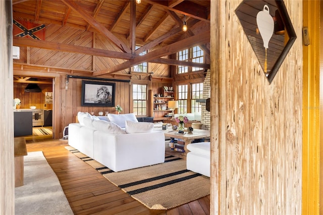 living room with vaulted ceiling with beams, light wood-type flooring, wood walls, and wood ceiling