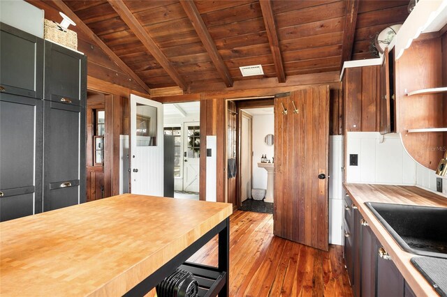 kitchen with lofted ceiling with beams, dark hardwood / wood-style flooring, wood ceiling, and wood counters