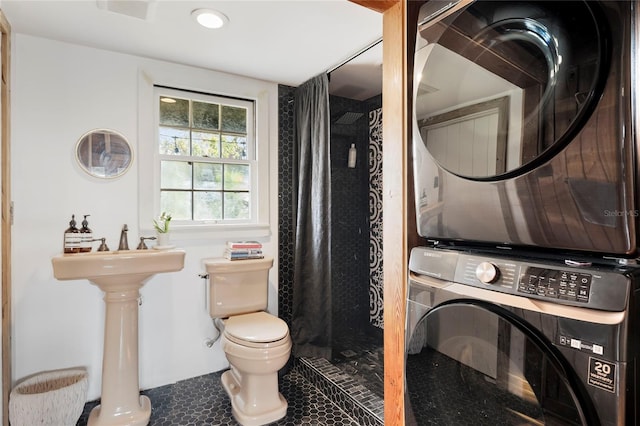 bathroom with toilet, a shower with curtain, tile patterned floors, and stacked washer and clothes dryer