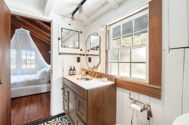 bathroom with beamed ceiling, hardwood / wood-style floors, plenty of natural light, and wood walls