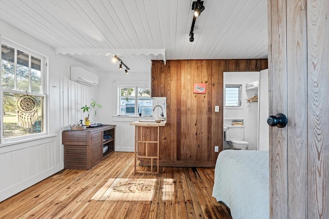 kitchen featuring a wall mounted AC, wood walls, track lighting, and light wood-type flooring